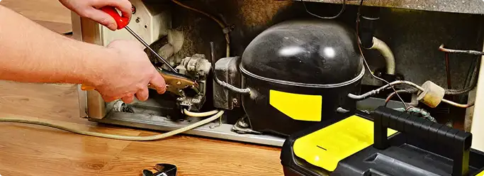 Refrigerator repair technician fixing the compressor and wiring in Kathleen, FL