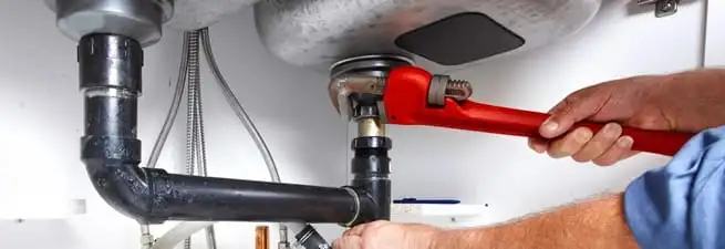 Garbage disposal repair technician tightening the sink drain and disposal connection in Lakeland, FL