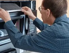 Appliance repair technician replacing a microwave vent filter in Lakeland, FL
