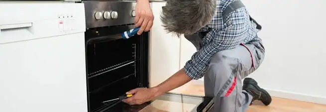 Oven repair technician inspecting and servicing an electric oven in Lakeland, FL