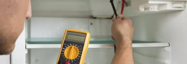 Refrigerator repair technician testing electrical components with a multimeter in Lakeland, FL