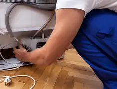 Appliance repair technician fixing refrigerator water line and connections in Lakeland, FL